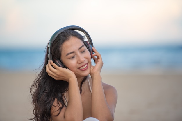 Glimlachende aantrekkelijke Aziatische vrouw met geluk en het genieten van op het strand