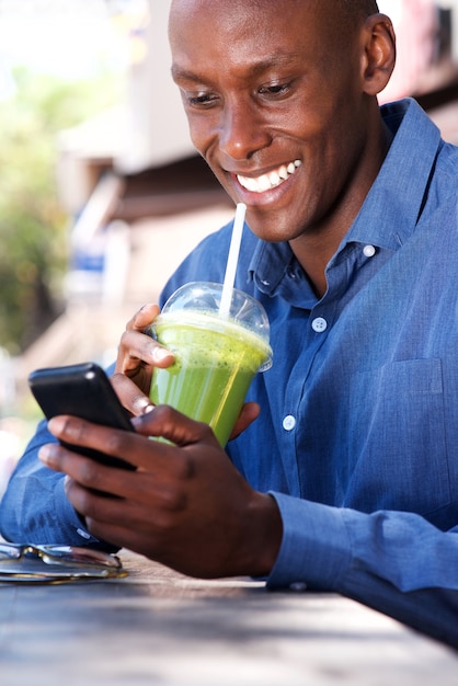 Glimlachende Afrikaanse Amerikaanse zakenman die cellphone gebruiken tijdens lunchpauze