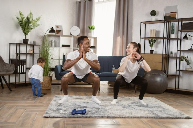 Glimlachende Afrikaanse man en blanke vrouw oefenen en squats doen