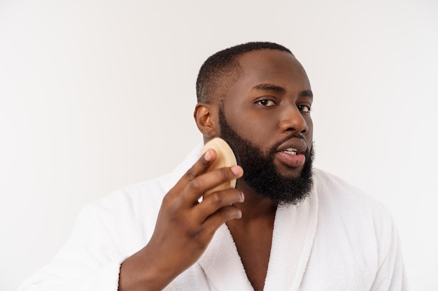 Glimlachende Afrikaanse man maakt zijn gezicht schoon met het huidverzorgingsconcept van de man
