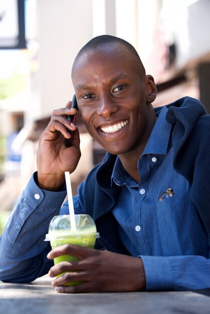 Glimlachende afrikaanse mensenzitting met mobiele telefoon en drank