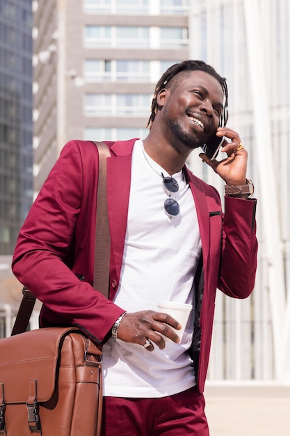 Glimlachende Afrikaanse zakenman loopt pratend via de telefoon