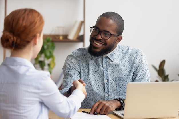 Glimlachende Afro-Amerikaanse HR-manager die de hand schudt van een kandidaat