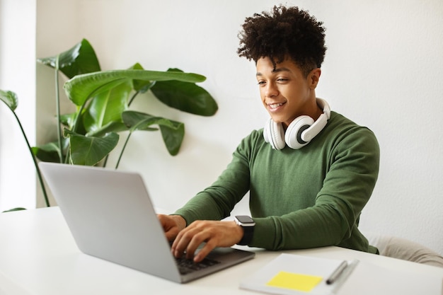 Foto glimlachende afro-amerikaanse man, onafhankelijke aannemer die op de computer tikt.