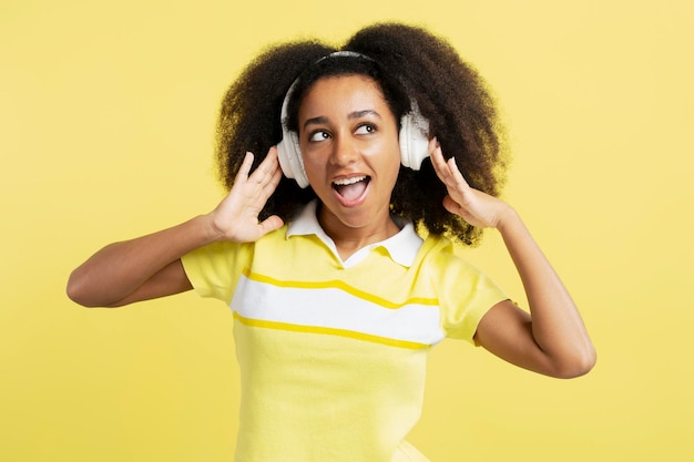 glimlachende Afro-Amerikaanse vrouw die een casual outfit draagt en plezier heeft met het luisteren van muziek in de koptelefoon