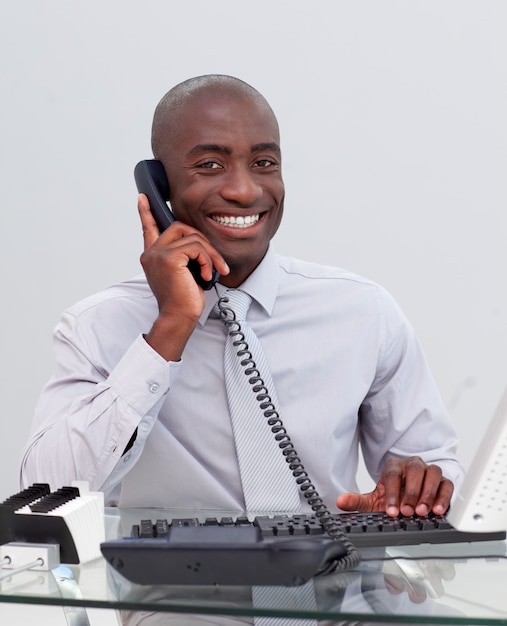 Glimlachende Afro-Amerikaanse zakenman op telefoon in het bureau