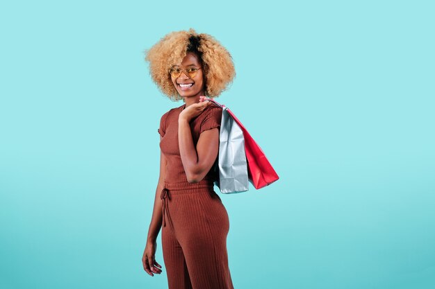 Glimlachende afrovrouw die kleurrijke winkelende papieren zakken draagt over een geïsoleerde achtergrond. Black Friday verkoopconcept.