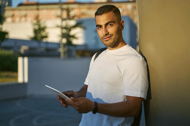 Glimlachende arabische man met digitale tablet kijkend naar de camera op straat