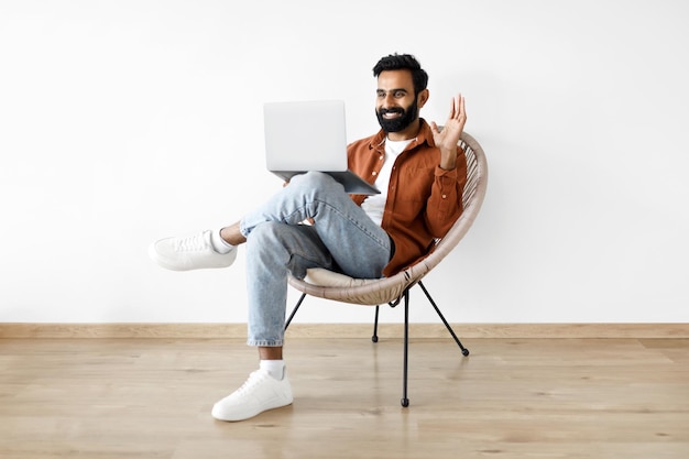 Glimlachende Arabische man zwaaien naar laptop webcam videobellen binnen