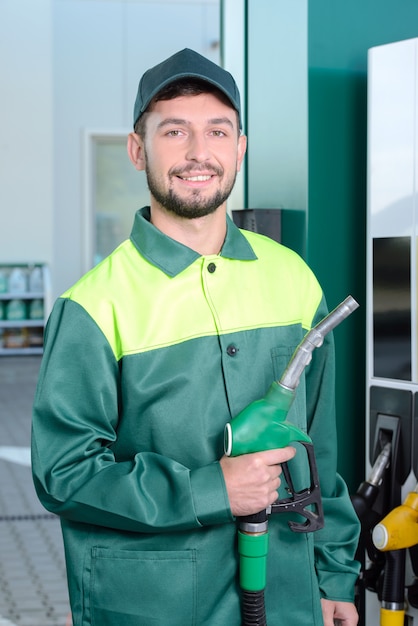 Glimlachende arbeider bij het benzinestation, terwijl het vullen van een auto