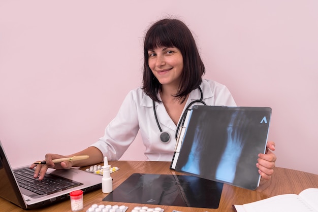 Glimlachende arts met laptop die de röntgenfoto van de patiënt toont