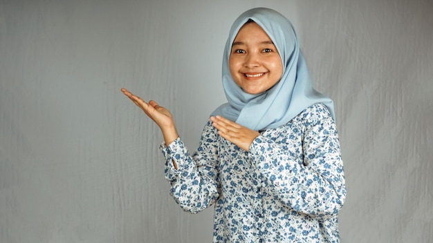 Glimlachende Aziatische hijabvrouw die omhoog wijst en naar de camera kijkt