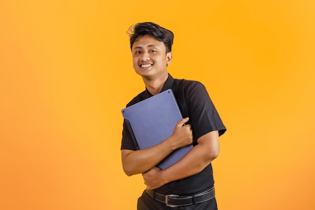Glimlachende Aziatische man die met laptopstudenten staat op weg naar de klas die zich voordeed op een gele pagina