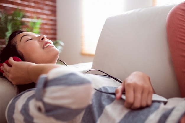 Foto glimlachende aziatische vrouw die op laag aan muziek luisteren