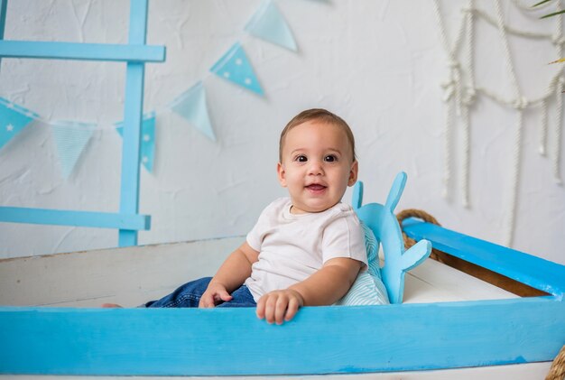 Glimlachende babyjongen en zit in een houten boot