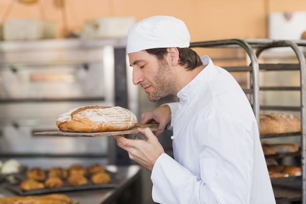 Glimlachende bakker die vers brood ruikt