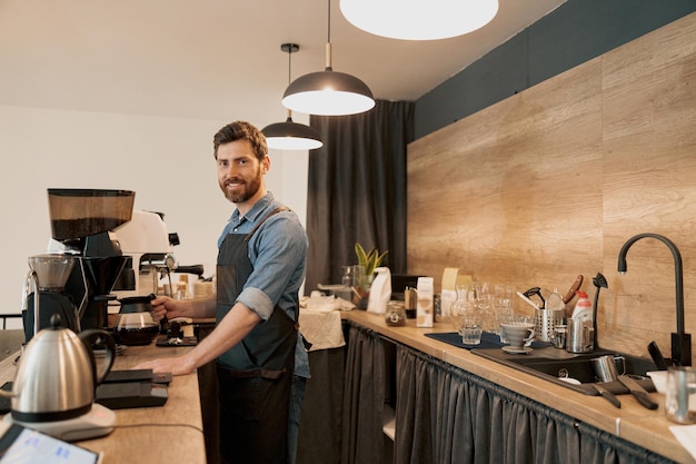 Glimlachende barista die glas vasthoudt met filterkoffie die achter de toonbank staat