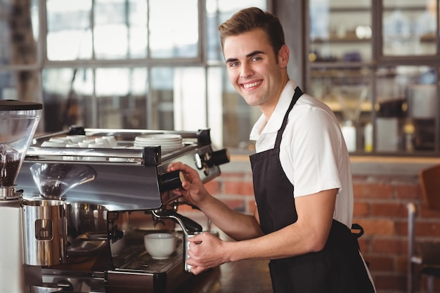 Glimlachende barista die melk stomen bij koffiemachine