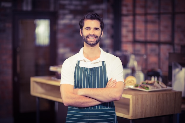 Glimlachende barista met gekruiste wapens