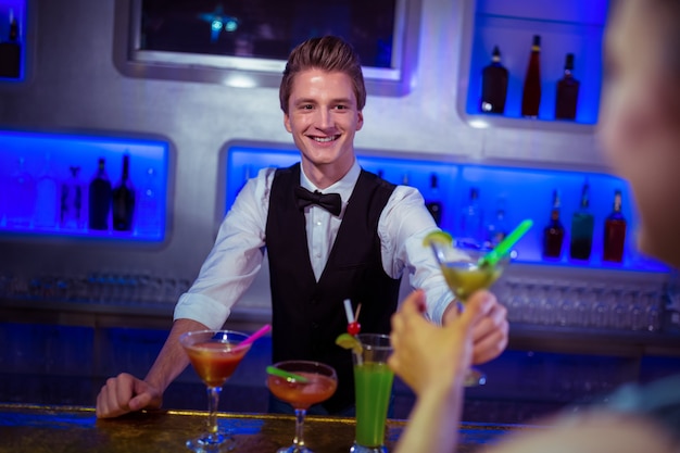 Glimlachende barman die cocktail dient aan vrouw