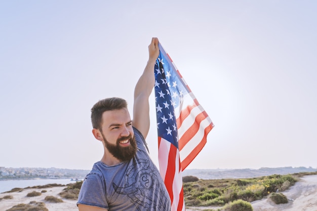 Glimlachende bebaarde man houden in opgeheven hand Amerikaanse vlag
