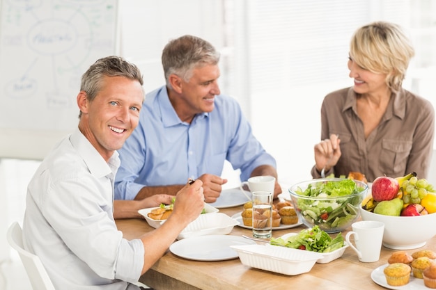 Glimlachende bedrijfscollega&#39;s die lunch hebben samen