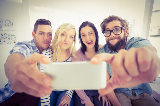 Glimlachende bedrijfsmensen die voor selfie stellen