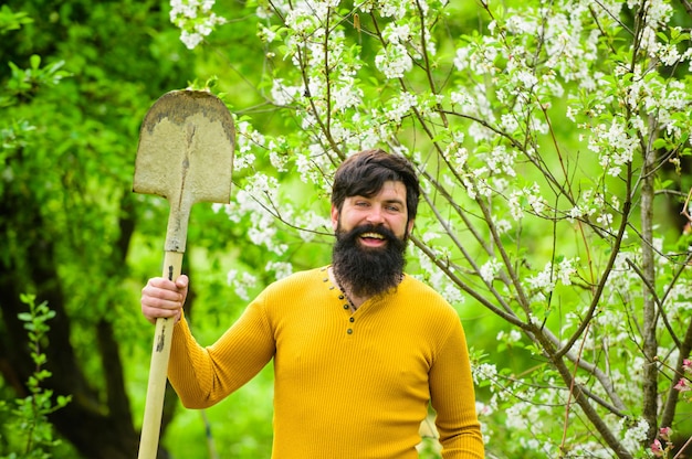 Glimlachende boerderijman die zich voorbereidt op het planten van tuinmanwerk, lentewerk in tuinboer die in de tuin werkt