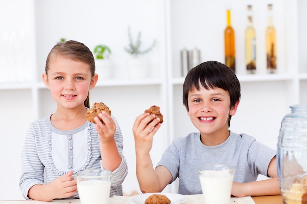 Glimlachende broer en zuster die koekjes en consumptiemelk eten