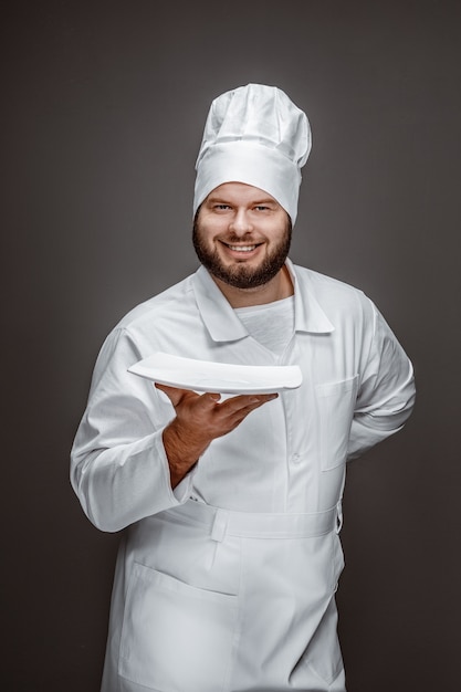 Glimlachende chef-kok die lege plaat voorstelt