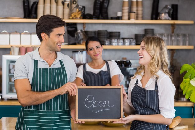 Glimlachende collega's die bord met open teken tonen