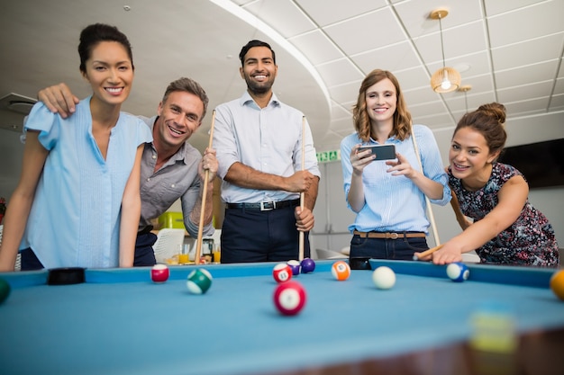 Glimlachende collega's pool spelen in kantoorruimte