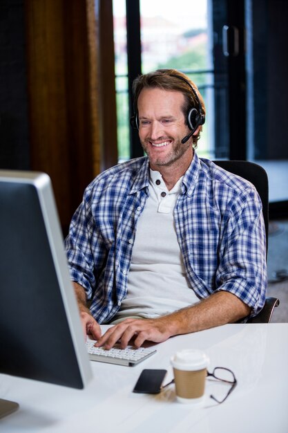 Glimlachende creatieve zakenman die aan computer werkt