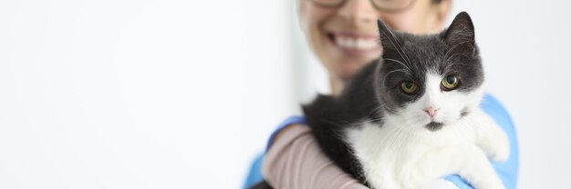 Glimlachende dierenarts houdt kat in zijn armen. Veterinaire kliniek diensten concept