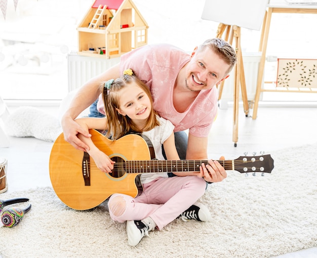 Glimlachende dochter met vader het spelen gitaar