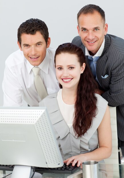 Glimlachende drie bedrijfsmensen die een computer met behulp van