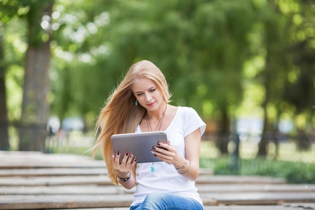 Glimlachende duizendjarige vrouw staan met behulp van moderne pad-gadget thuis surfen op internet of winkelen gelukkig tevreden jonge vrouwelijke klant surfen op het web nieuws lezen of chatten op tablet apparaat technologie concept