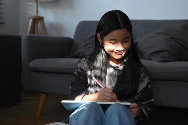 Glimlachende elementaire student huiswerk in woonkamer