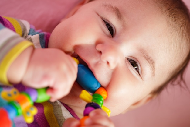 Glimlachende en spelende baby met bijtring. Close-up gezicht.
