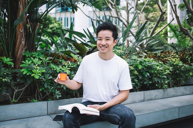 Glimlachende etnische man die van espresso geniet tijdens het lezen in de tuin
