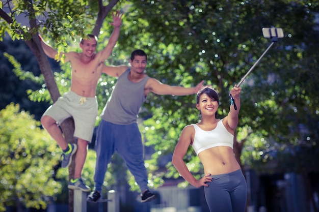 Glimlachende extreme atleten die selfies met selfiestick nemen