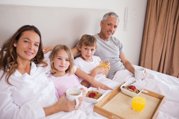 Glimlachende familie die ontbijt in een slaapkamer heeft