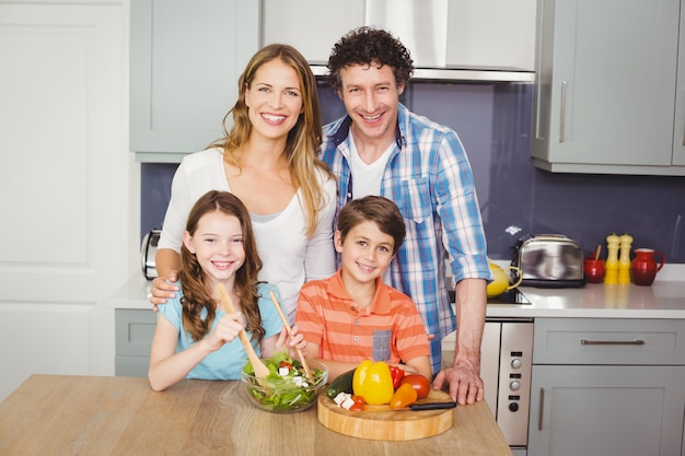 Glimlachende familie die plantaardige salade voorbereidt