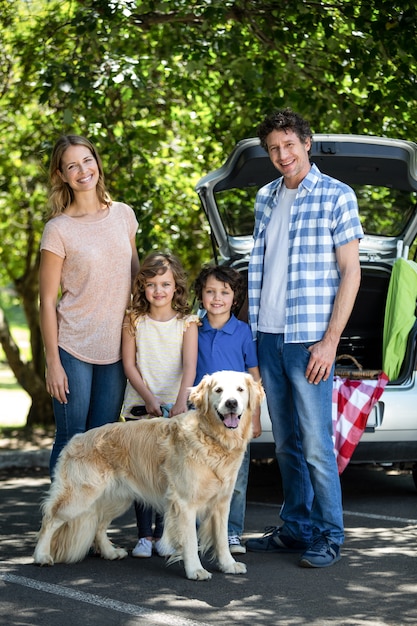 Glimlachende familie die zich voor een auto bevindt