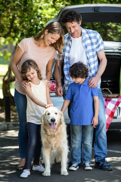 Glimlachende familie die zich voor een auto bevindt