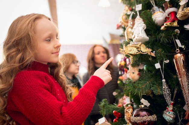 Glimlachende familiemoeder en kinderen die op zoek zijn naar woondecoratie en vakantiegeschenken in een huishoudelijke winkel