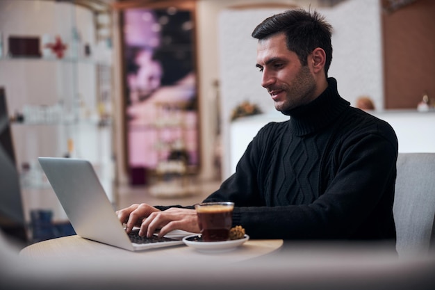 Glimlachende freelancer die op internet in de hotellobby werkt