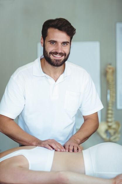 Glimlachende fysiotherapeut die massage teruggeven aan een vrouw