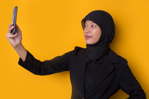 Glimlachende gelukkige Aziatische moslimonderneemster die een selfie neemt