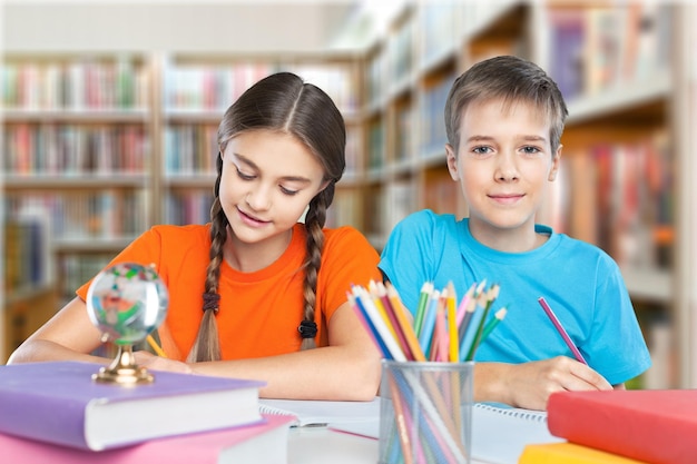 Glimlachende gelukkige kinderen die tijdens de les bij de tafel zitten